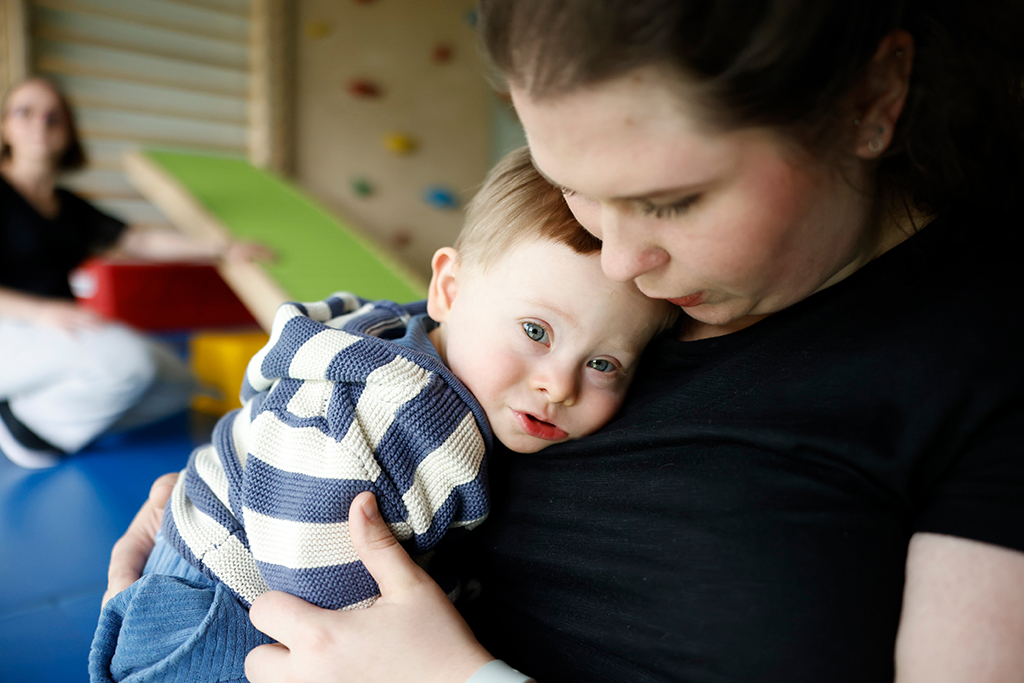 Eine Mitarbeiterin der Integrativen Kindereinrichtungen hält ein Kind im Arm.