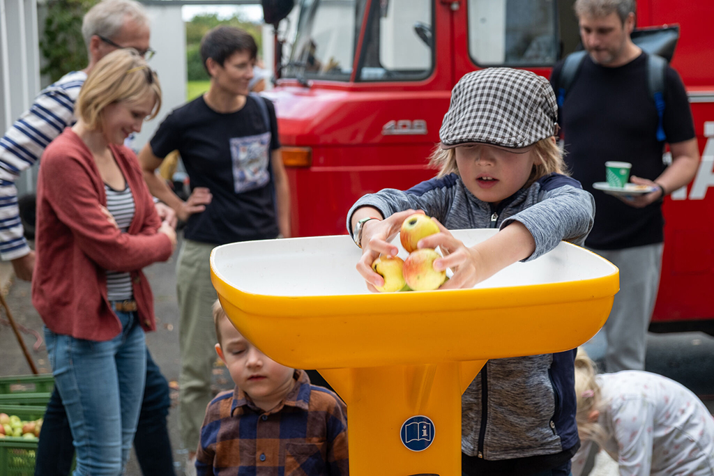 Beim Hof- und Kelterfest: Ein Junge legt Äpfel in die Keltermaschine.