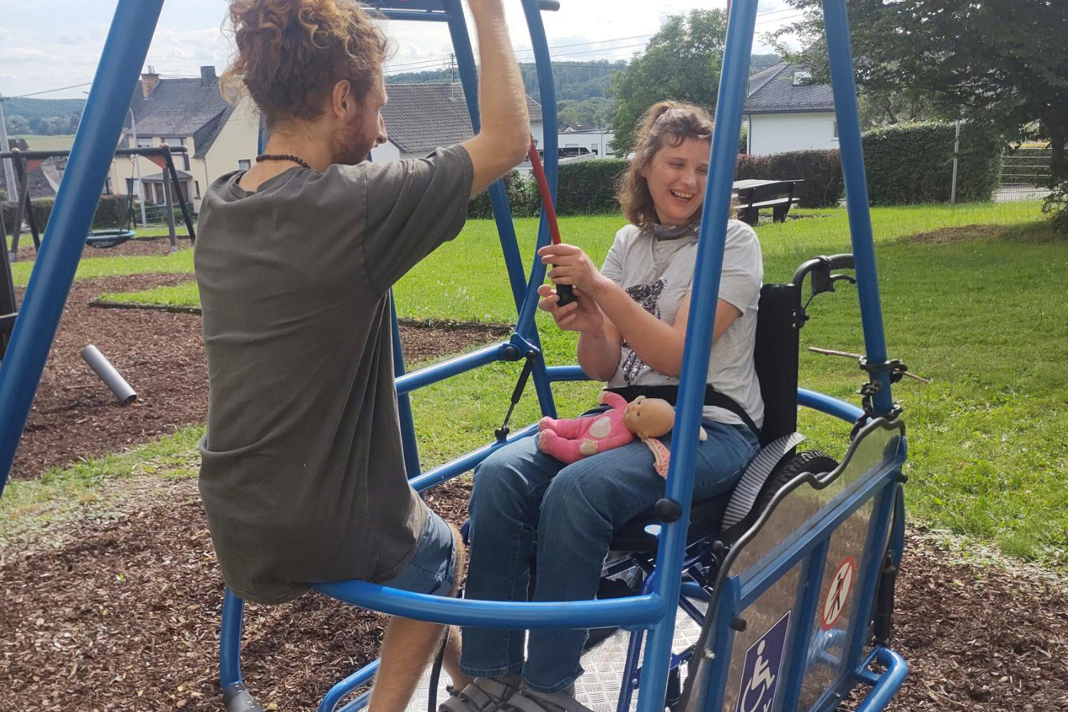 Urlauberin und Assistenz auf einer Rollstuhl-Schaukel.