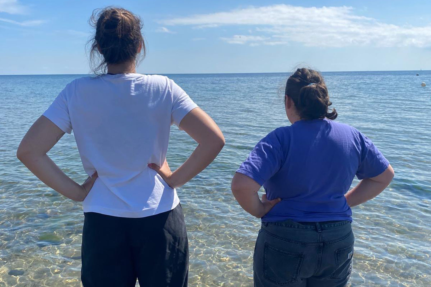 Urlauberin und Assistenz schauen aufs Meer hinaus.