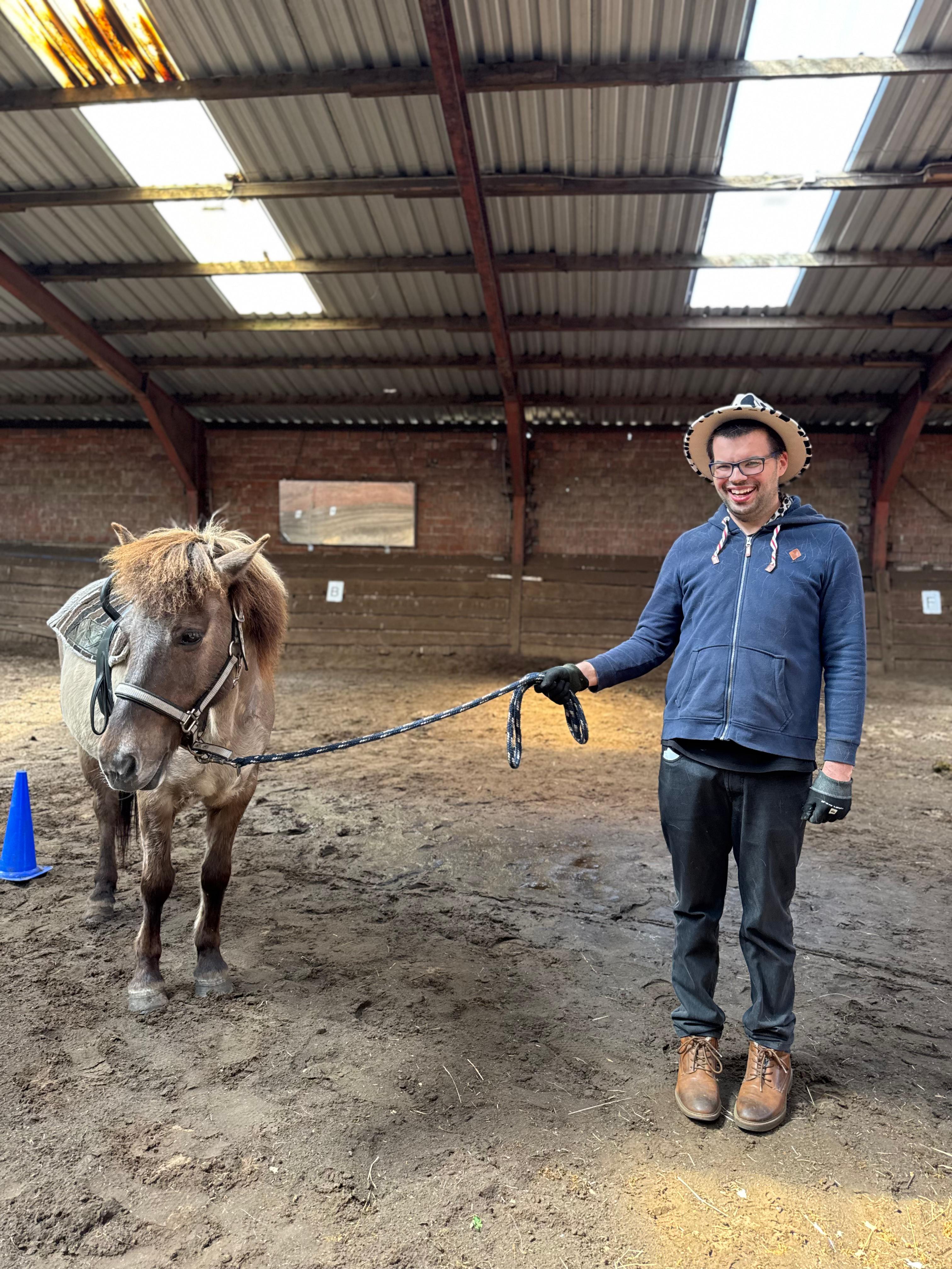 Ein glücklicher Urlauber hält die Leine eines Pferdes.