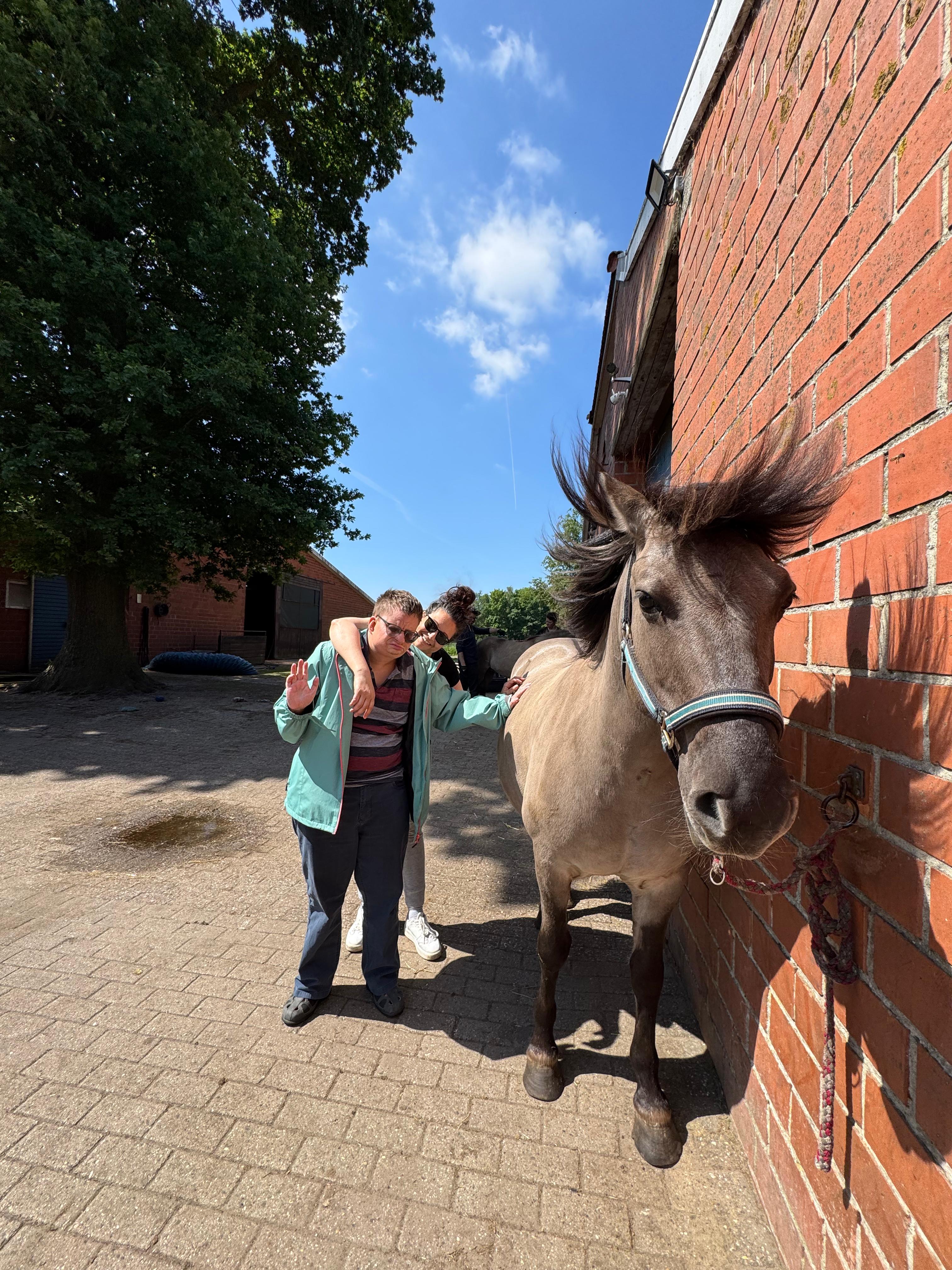 Ein Urlauber streichelt ein Pferd.
