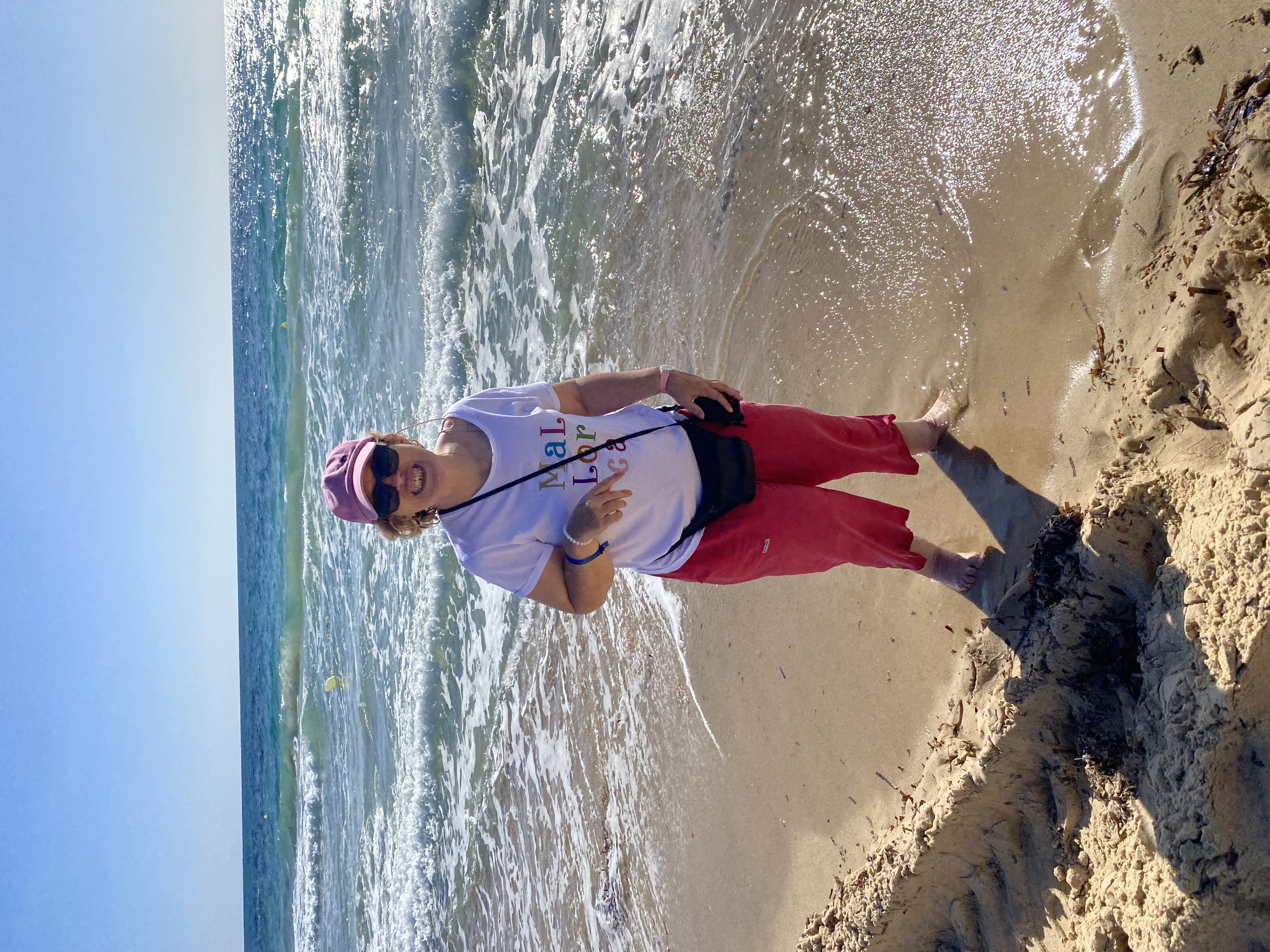 Eine zufriedene Urlauberin steht am Meer.