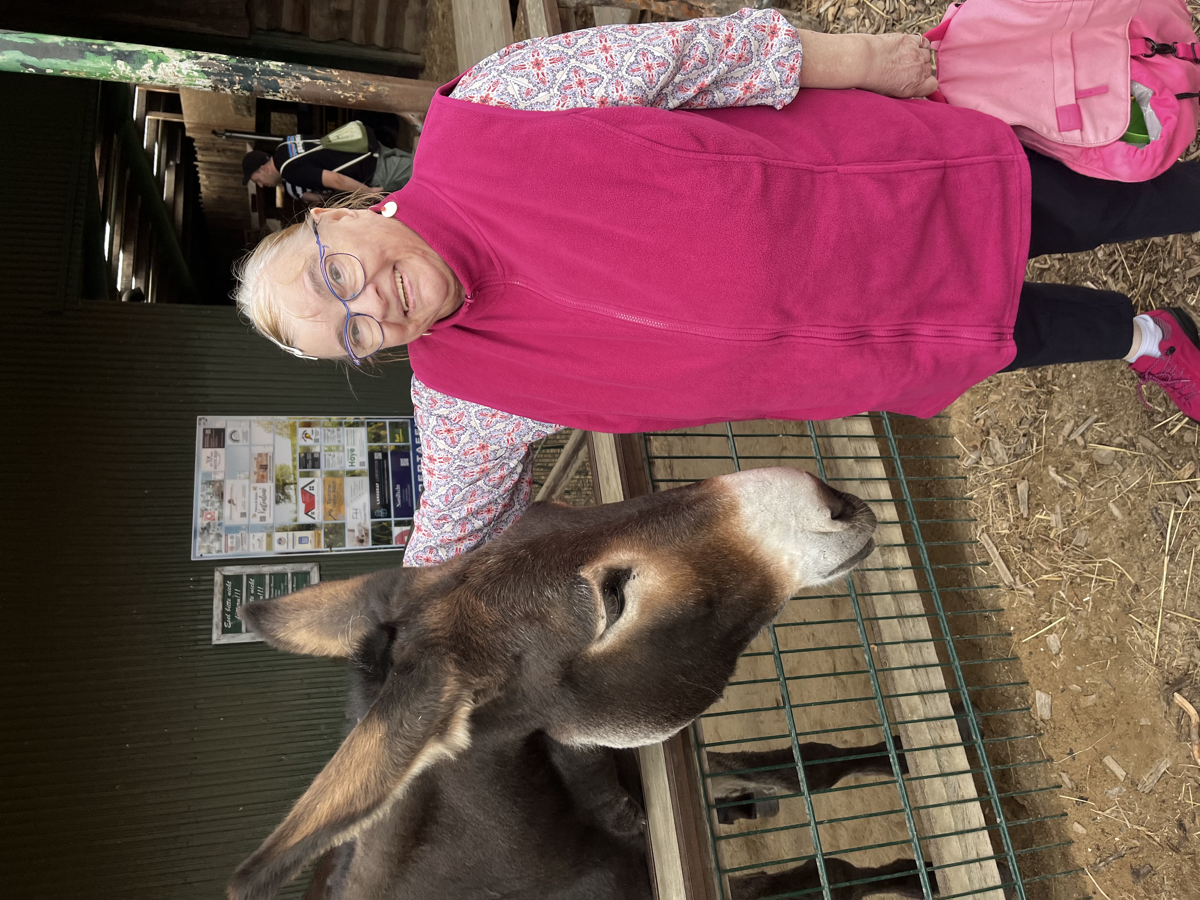 Eine Urlauberin hat Freude daran einen Esel zu streicheln.